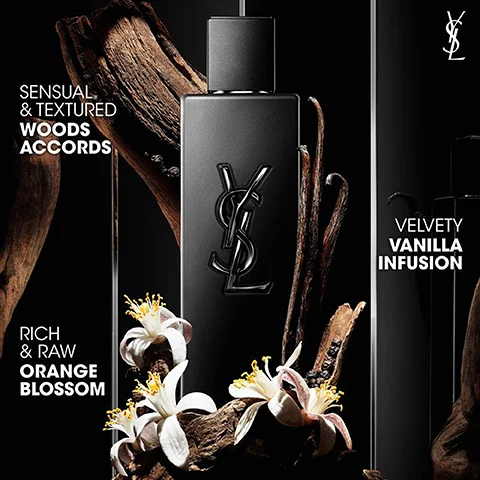 A black rectangular perfume bottle with a raised YSL logo on its front is depicted amidst wooden fragments, vanilla pods, and white orange blossom flowers against a dark background, accompanied by text that reads SENSUAL & TEXTURED WOODS ACCORDS, RICH & RAW ORANGE BLOSSOM, VELVETY VANILLA INFUSION, and the YSL logo.